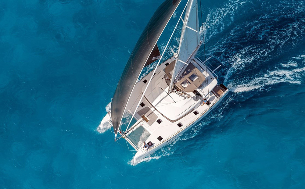 A yacht sailing in the blue sea near Santorini, where Omna Caldera Suites are located.