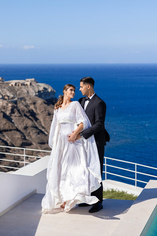 A couple at a balcony with sea view celebrating love at Omna Caldera Suites with sea view.