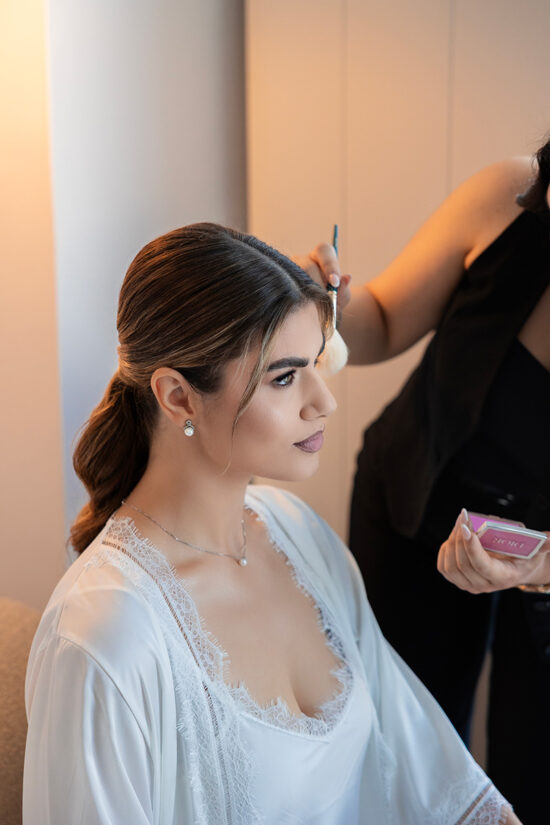 A makeup artist applying makeup to a bride at Omma Caldera Suites in Santorini.