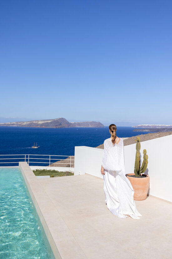 A bride walking by a pool, admiring the sea view at Omna Caldera Suites in Santorini.