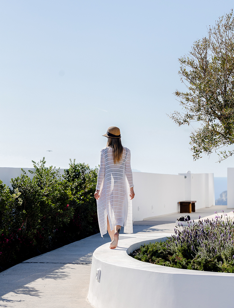 Lady walking on a white flower bed in the garden of the Luxury Suites in Santorini.